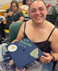 a woman holds up her decorated graduation cap