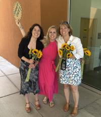 three adults stand together at graduation ceremony