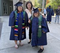 a professor with two students in caps and gowns