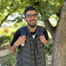 student standing near tree with backpack