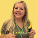 sarah with a banana statue in one hand and giving a thumbs up with the other