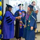 a redwood seed scholar walks across the room shaking hands with a line of people and getting a diploma