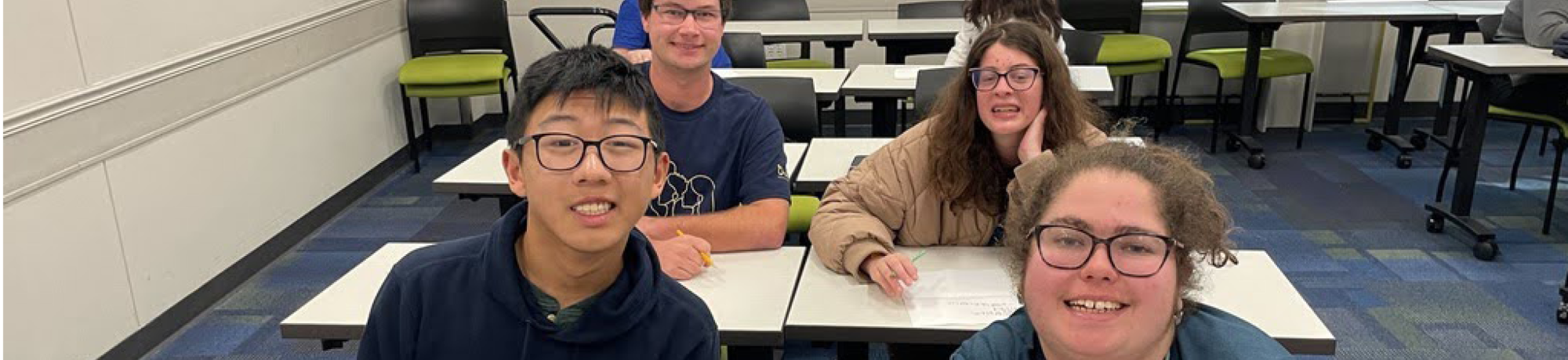 four students sitting at desks in a classroom