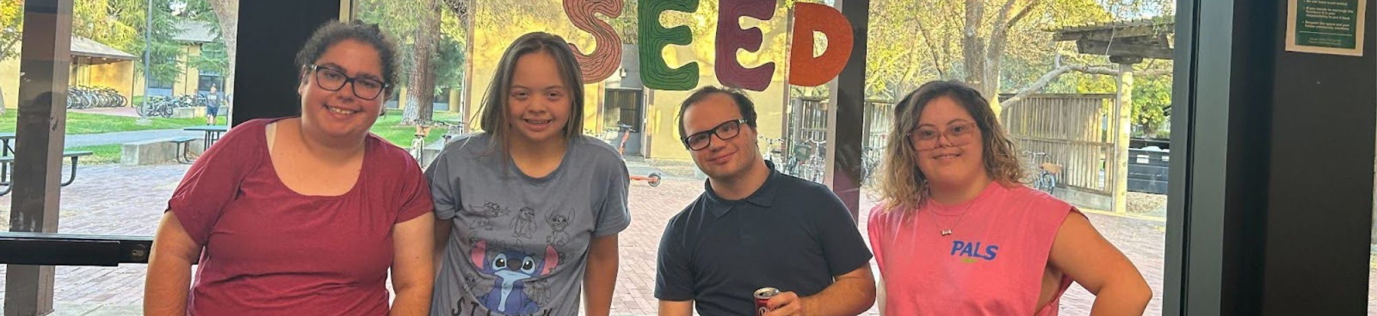four students standing together and smiling for the camera