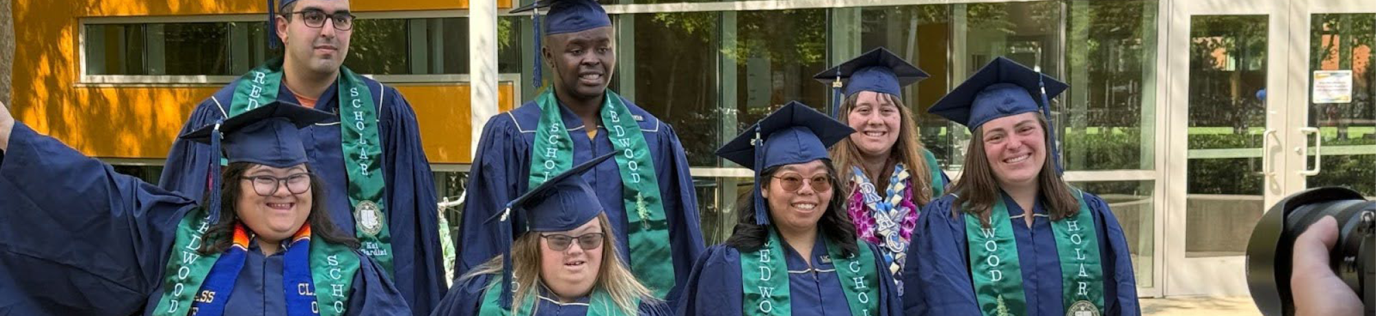 group of seven students posing together in their graduation gowns and hats