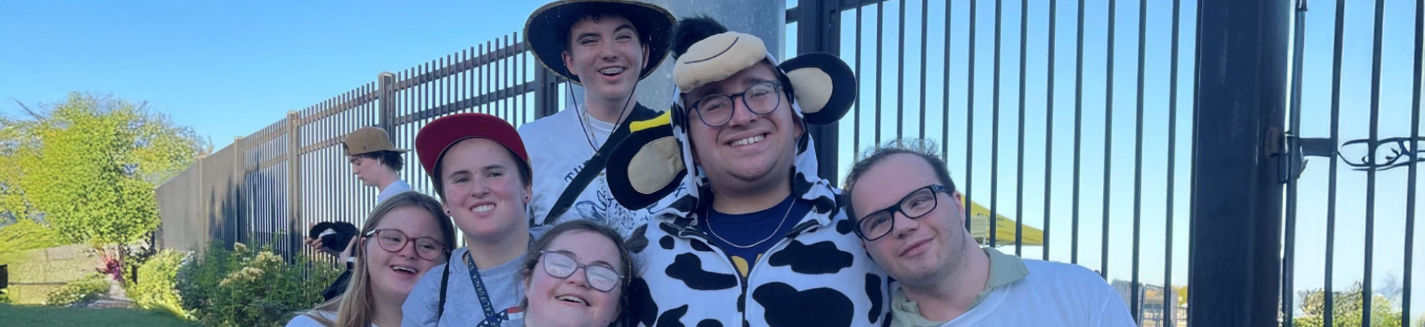 group photo of six students at an event, five are wearing tshirts that say the aggie pack, one is wearing a cow costume